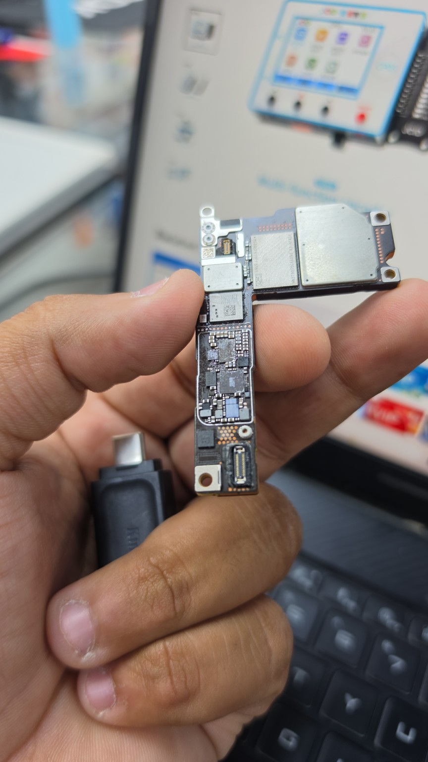 iPhone 16 motherboard held outside the handset with a section of its circuitry exposed