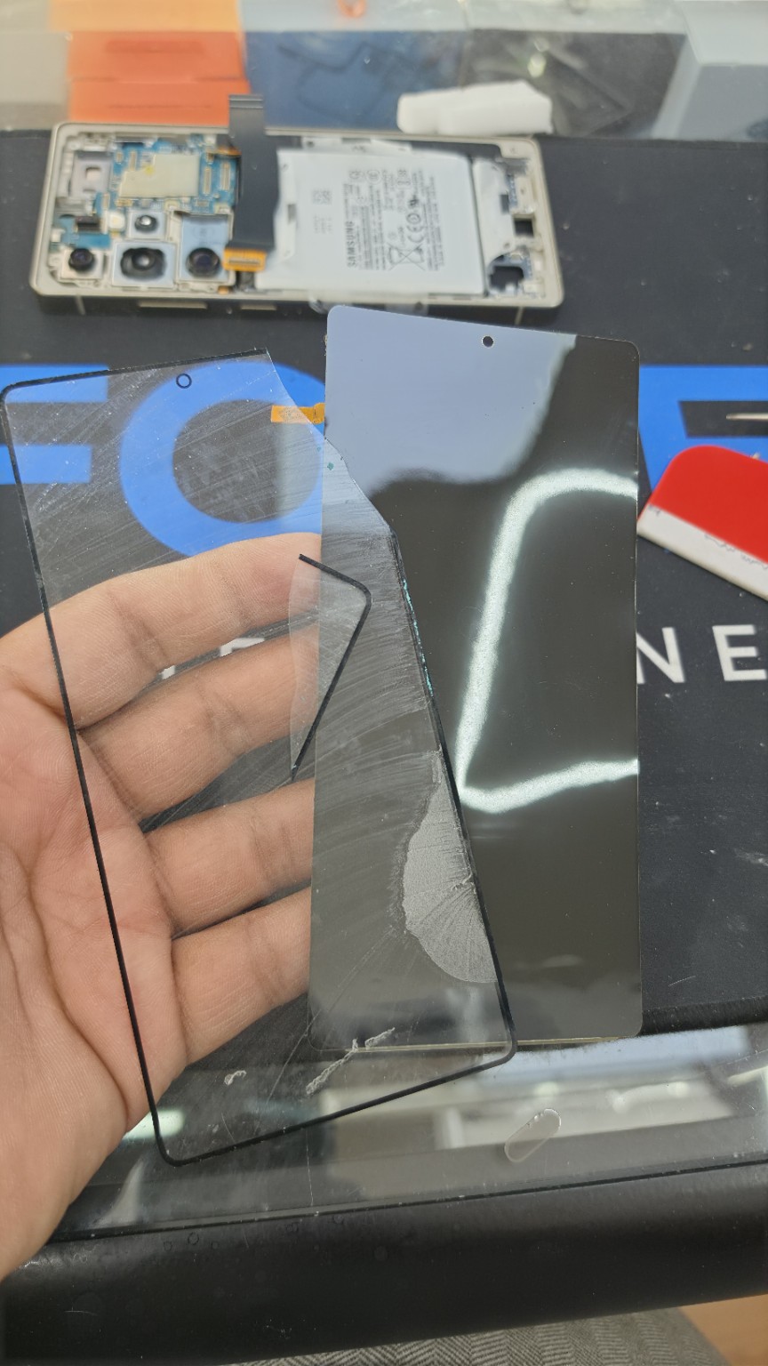 Removed Samsung S25 Ultra front glass held beside the separate display on the Fonebook repair bench